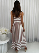 Woman wearing a striped dress standing in front of white curtains
