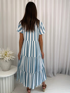 Woman wearing a blue and white striped dress against a neutral background