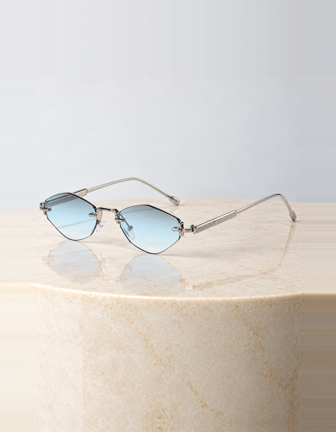 Women's rimless mini hexagonal sunglasses with silver tone arms and icy blue tinted lenses, the Dove Sunglasses in Blue by Esther & Co