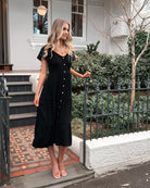 Women wearing the Celie Dress in Black, a relaxed linen midi dress with V-neckline and button-up front