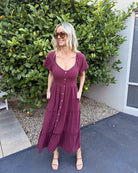 Model wearing the Celie Bordeaux Dress styled with tan sandals for a casual brunch look