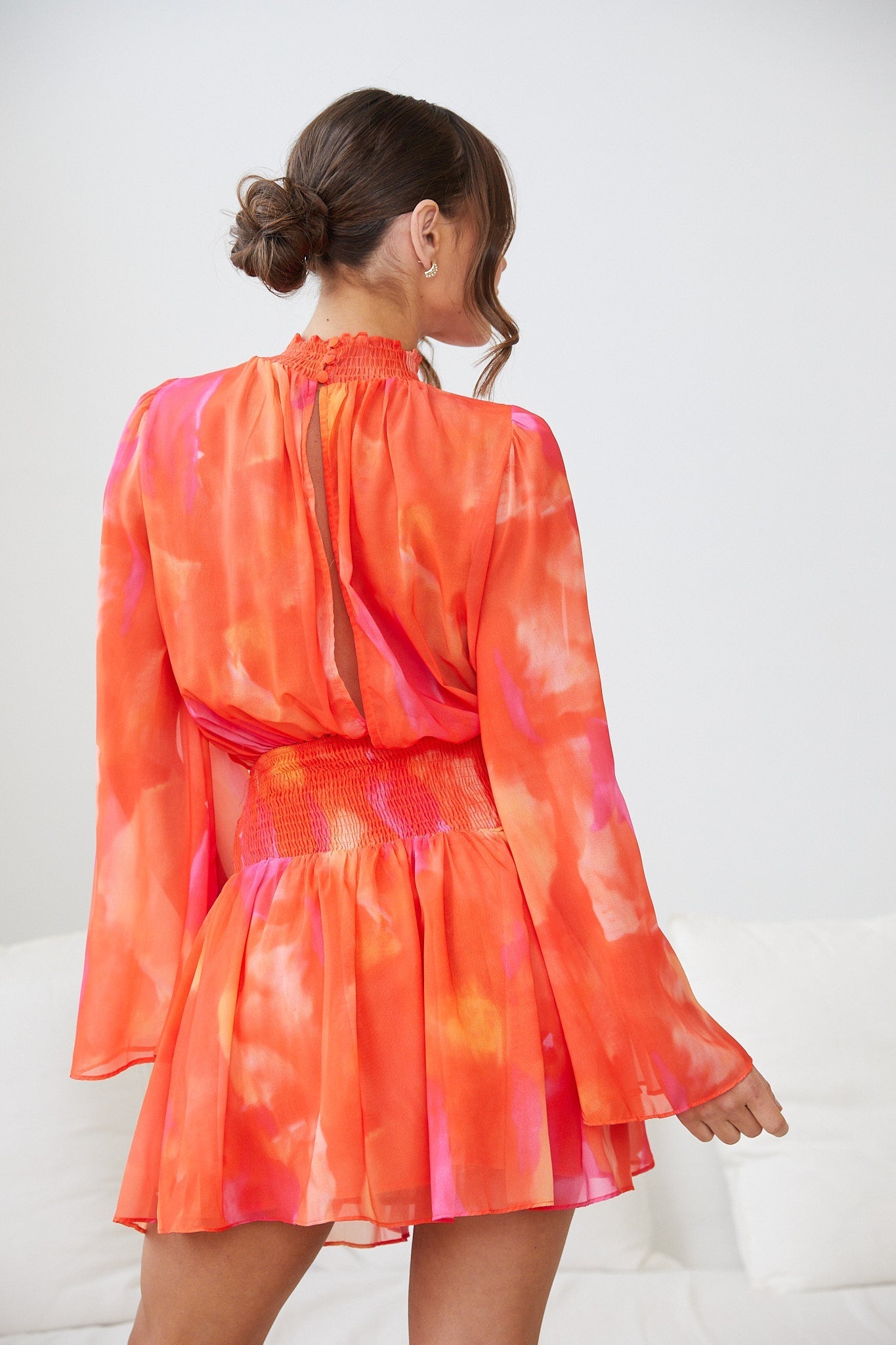 Front view of the Daenerys Mini Dress in Orange Print showing the smocked bodice and high neck detail