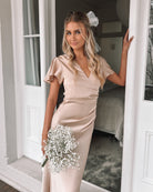 Women wearing the Doren Dress in Champagne, a formal satin maxi dress with V-neckline from the Esther Luxe Collection