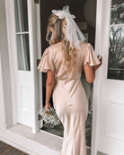 Side view of the Doren Dress in Champagne showing the short sleeves and floor-grazing maxi length