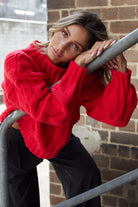 Women wearing the Hadi Knit in Red, a cosy acrylic women's jumper with high round neckline and long sleeves