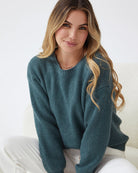 Women wearing the Harvie Knit in Petrol, a soft wool blend jumper in rich deep teal with round neckline and long sleeves