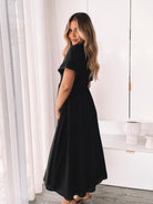 Side view of the Iolana Dress in Black showing the flowing A-line skirt and short sleeves