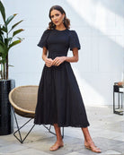 Women wearing the Iolana Dress in Black, a flattering cotton smock midi dress with round neckline and short sleeves