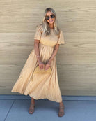 Women wearing the Iolana Dress in Beige, a neutral cotton smock midi dress with round neckline and textured chest detail