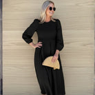 Women wearing the Iolana Dress in Black Long Sleeve, a cotton midi dress with round neckline and smocked bodice