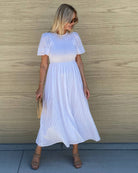 Women wearing the Iolana Dress in White, a classic cotton smock midi dress with round neckline and short sleeves