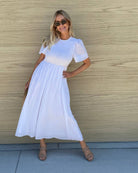 Model wearing the Iolana Dress in White styled with tan sandals for a bridal shower look