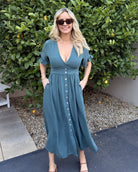 Women wearing the Korbela Dress in Deep Green, a relaxed linen blend midi dress with V-neckline and spot print