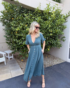 Model wearing the Korbela Deep Green Midi Dress styled with tan sandals for a casual summer look