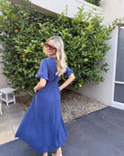 Side view of the Korbela Dress in Navy showing the flowing midi length and spot print fabric