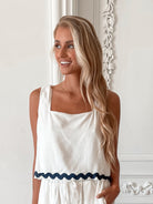 A woman wearing a white crop top with a square neckline and semi-relaxed fit, in a room with classic decor.
