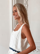 A woman wearing a white crop top with a square neckline and semi-relaxed fit, in a room with classic decor.