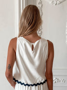 A woman wearing a white crop top with a square neckline and semi-relaxed fit, in a room with classic decor.
