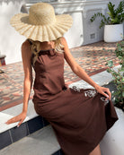 Women wearing the Syvella Dress in Brown Floral, a flowing women's maxi dress with square neckline and wide straps in brown and white floral print