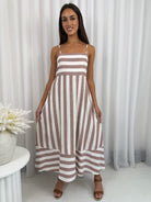 Woman wearing a brown and white striped dress against a white curtain background