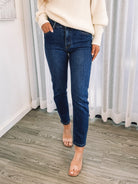 A person wearing a dark blue high-waisted, skinny fit pair of jeans with side pockets and a button and quarter zip closure.