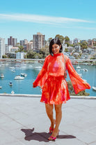 Influencer wearing the Daenerys Orange Print Mini Dress from Esther and Co