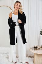 Side view of the Fireplace Coat in Black showing the longline fit and long sleeves with cuff detail