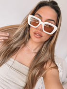 A pair of beige sunglasses displayed on a surface.