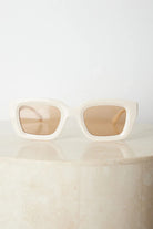 A pair of beige sunglasses displayed on a surface.