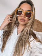 A pair of sunglasses with a tan frame displayed on a surface.