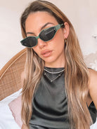 Green geometric-shaped sunglasses with dark lenses resting on a light marble surface against a plain white background.