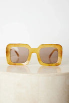 A pair of sunglasses with a tan frame displayed on a surface.