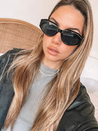 A pair of black sunglasses displayed against a neutral background.