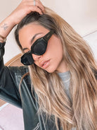 A pair of black sunglasses displayed against a neutral background.