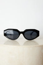 A pair of black sunglasses displayed against a neutral background.