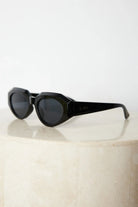 A pair of black sunglasses displayed against a neutral background.
